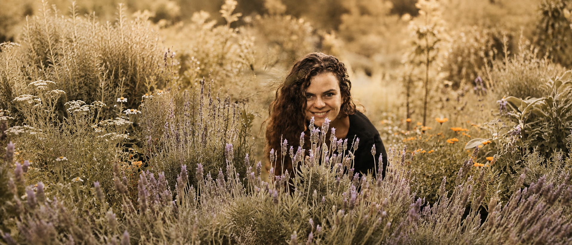 Naty Tataendy sorrindo em meio a um campo de lavandas e ervas medicinais