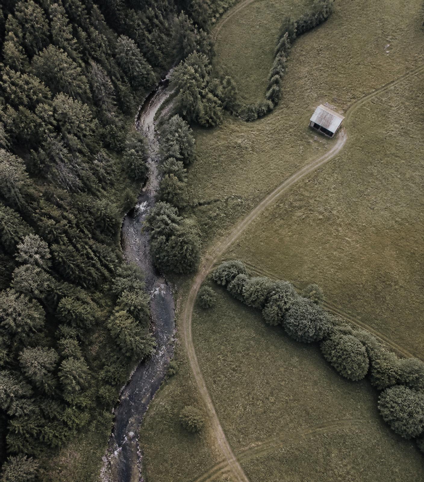 Vista aérea de um terreno rural com curso d'água, mata e área aberta